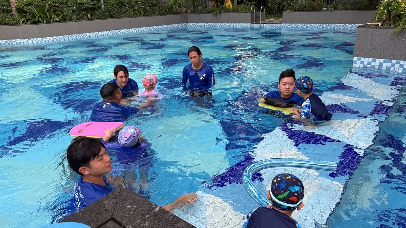 Penguin Academy coaches leading children through in-water attachment practice at a Singapore swimming pool