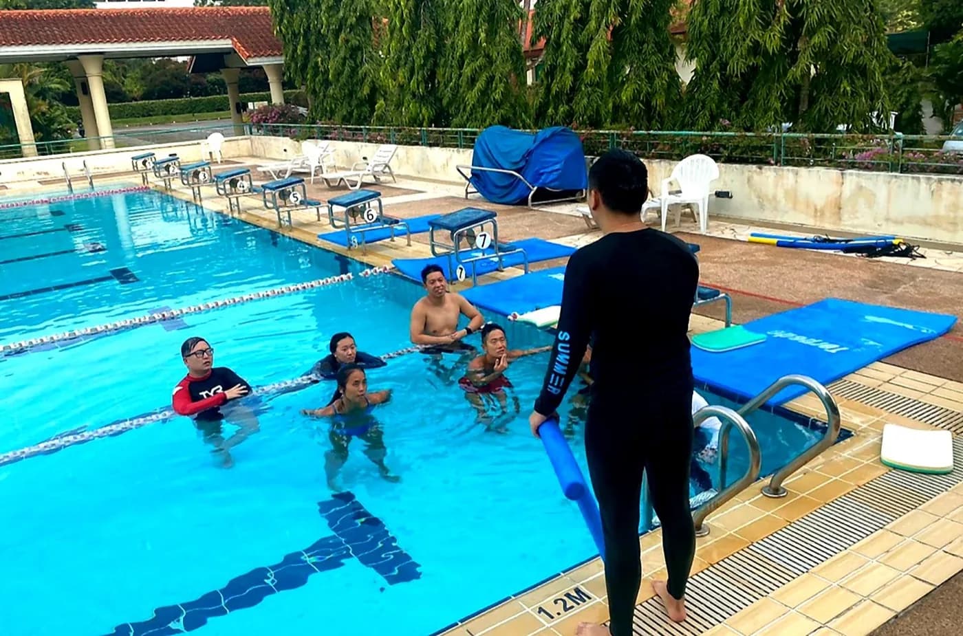 Penguin Academy in-water swim teacher briefing with candidates at a Singapore training pool
