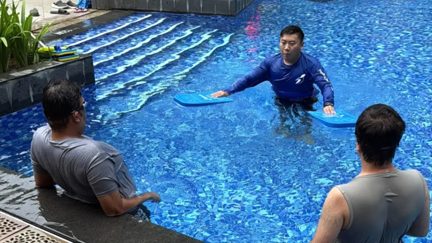Penguin Swim School coach guiding two adult learners during an adult private swimming lesson