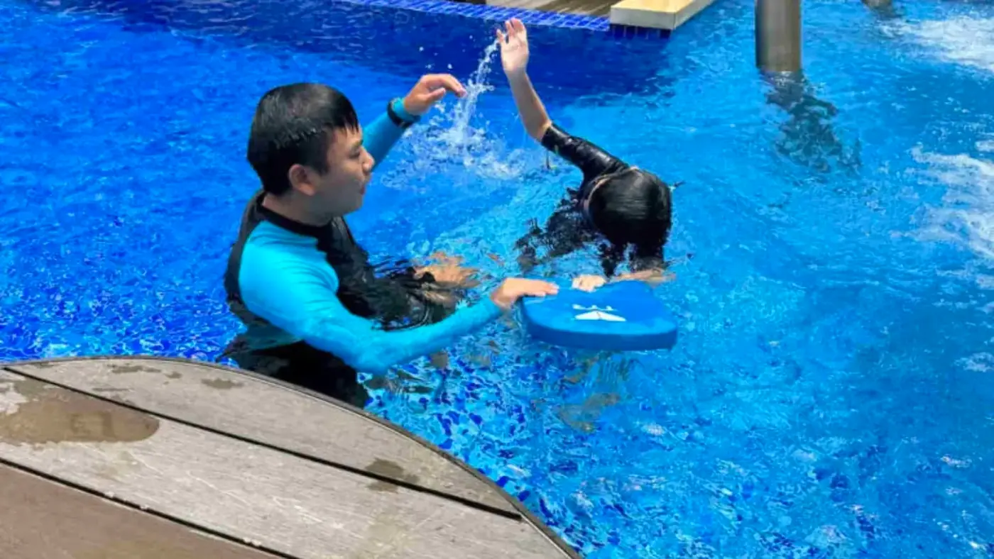 Penguin Swim School coach giving close in-water correction to a child during a private swimming lesson