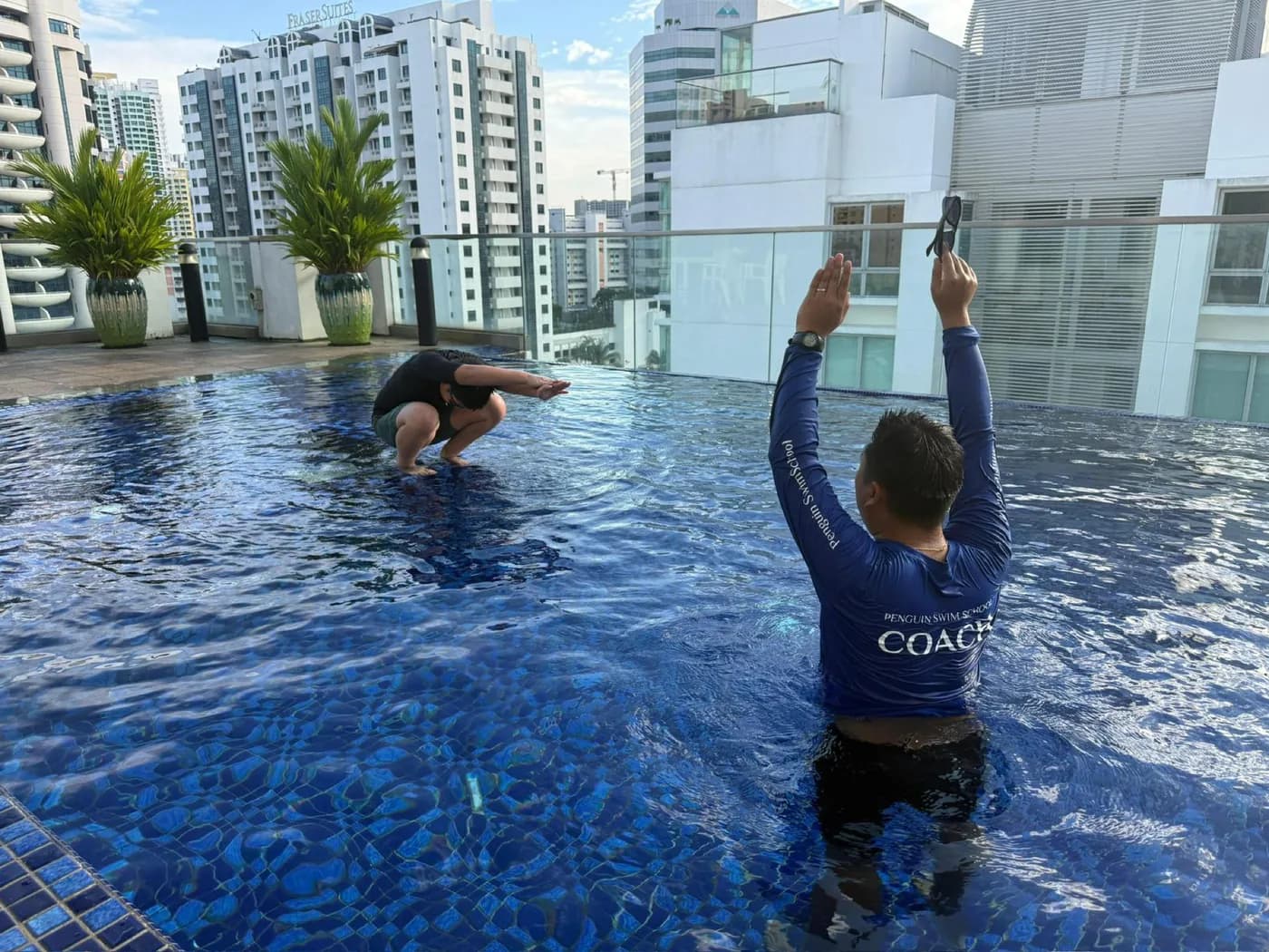 Penguin Swim School coach demonstrating a movement cue during a rooftop practical lesson